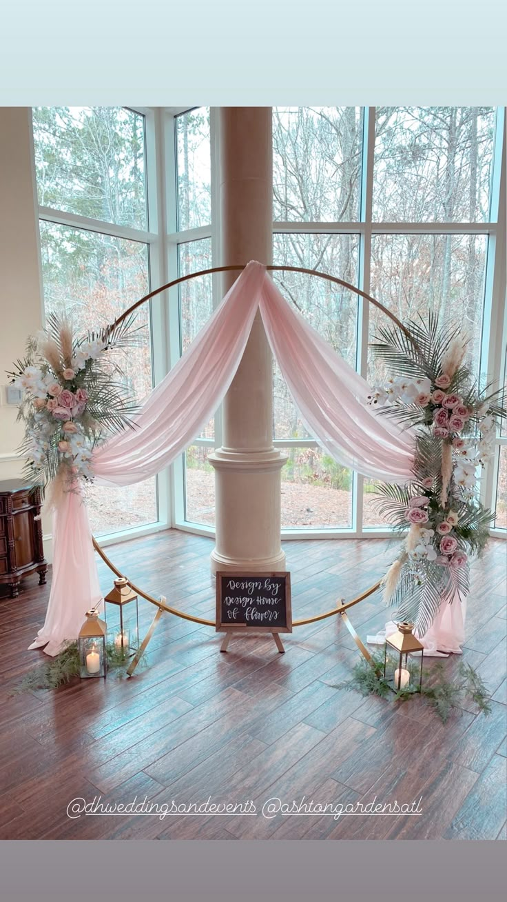 an arch decorated with flowers and greenery in front of a window at a wedding