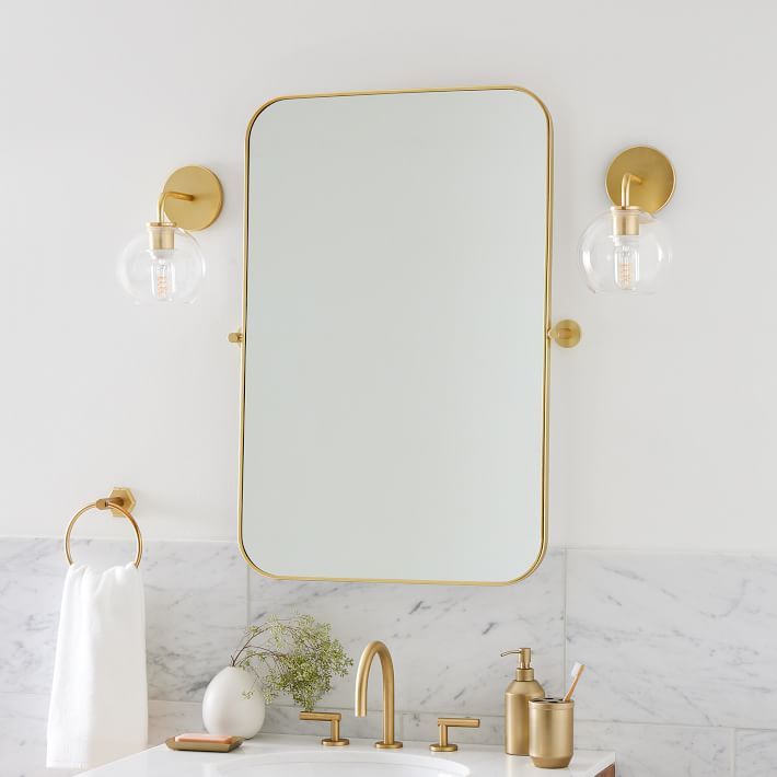 a bathroom with marble countertops and gold fixtures, including a large mirror above the sink