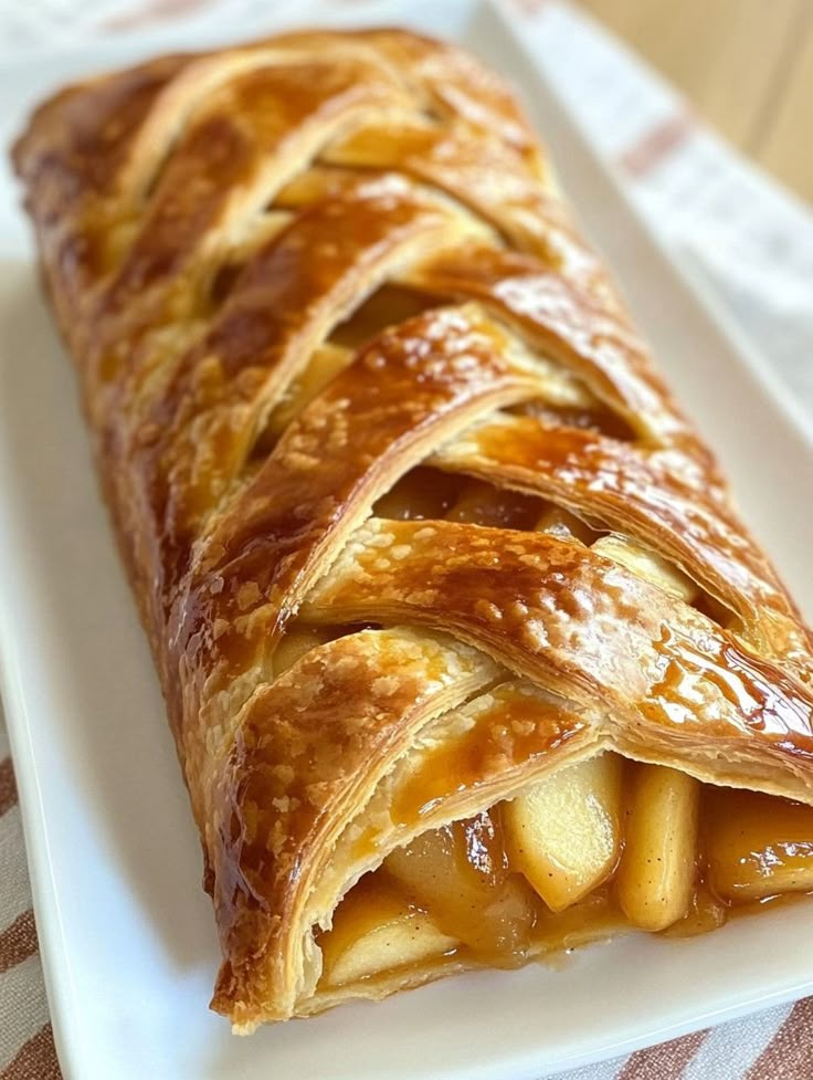 a pastry on a white plate with apples in the center and caramel toppings