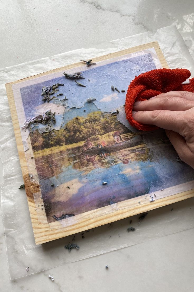 someone is holding up an old photo to show it's reflection in the water