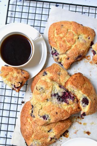 blueberry scones on a cooling rack next to a cup of coffee and saucer