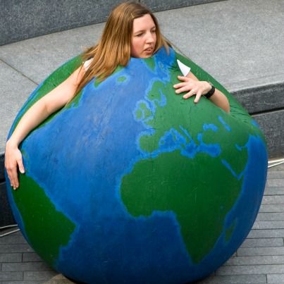 a woman sitting on top of a giant blue and green globe