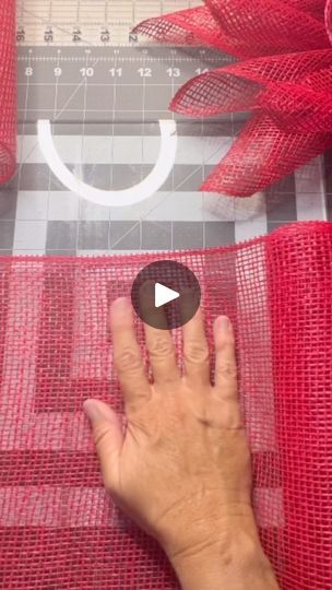 a person's hand on top of a red mesh curtain next to a ruler