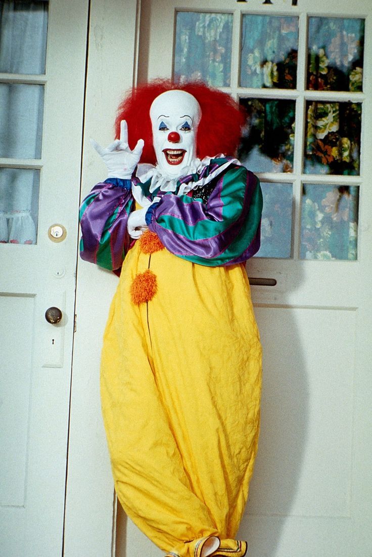 a creepy clown standing in front of a door