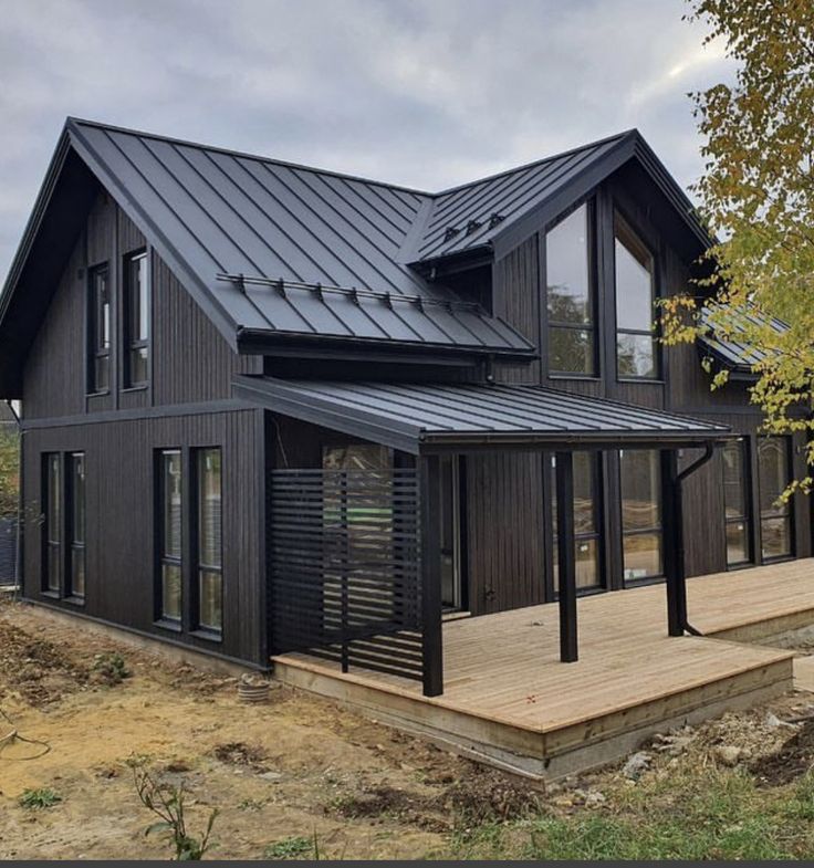 a black house with a metal roof and wooden steps leading up to the front door