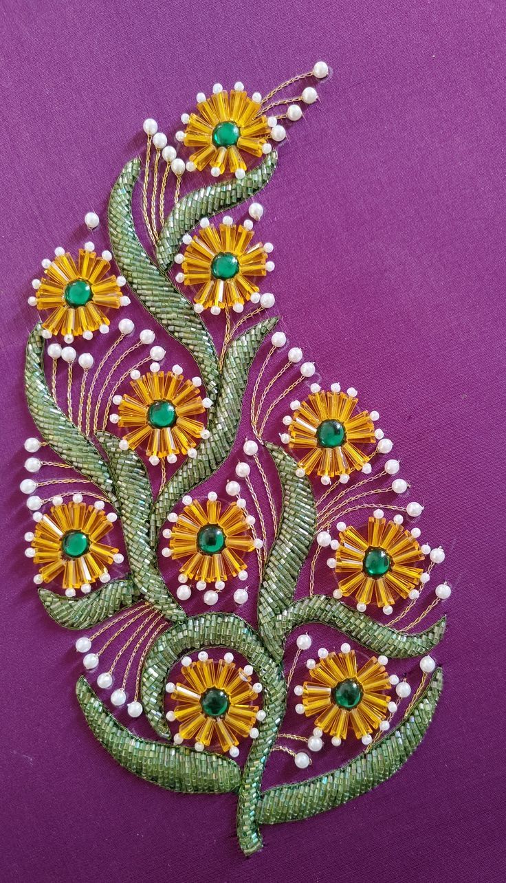 an embroidered piece with flowers and pearls on purple fabric, showing the back side of it