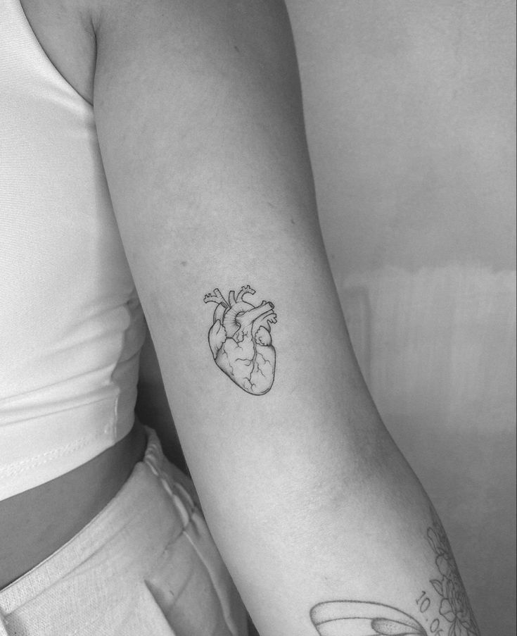 a woman's arm with a heart tattoo on it