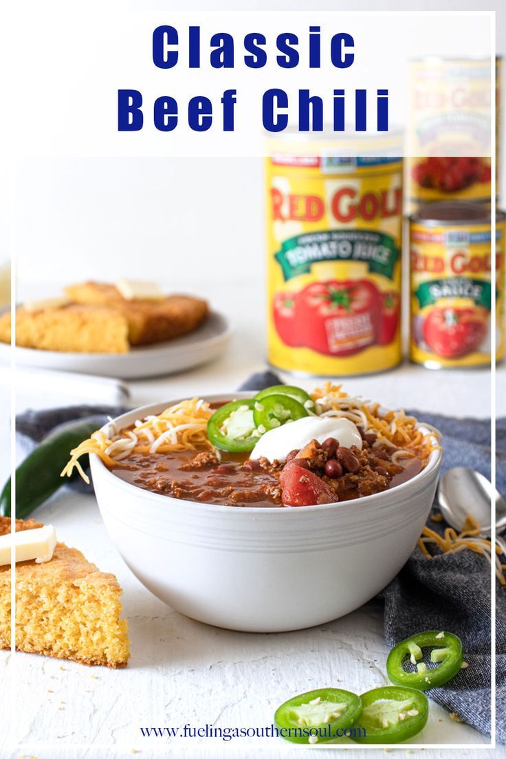 a white bowl filled with beef chili next to some crackers and green peppers on the side