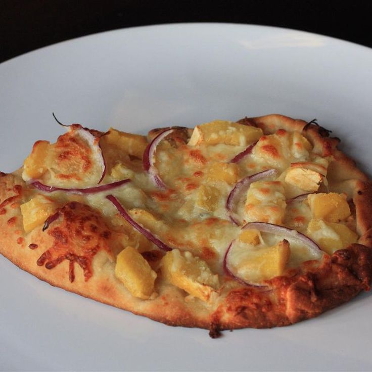 a slice of pizza with onions and cheese on a white plate, ready to be eaten