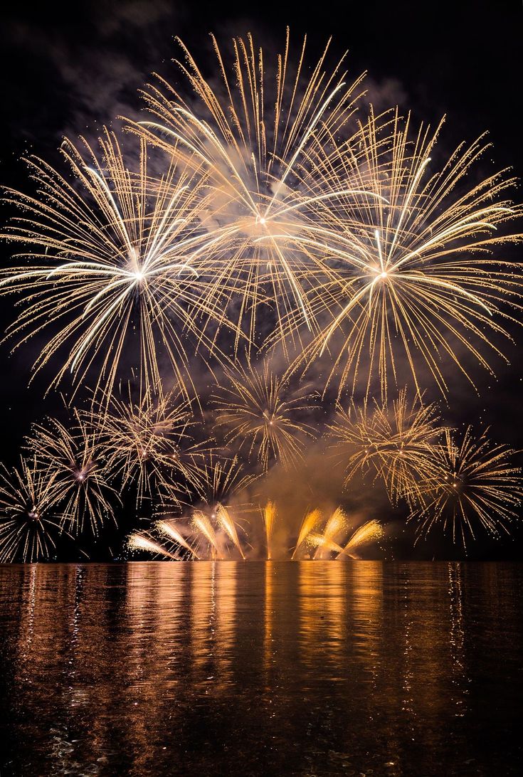 fireworks are lit up in the night sky over water