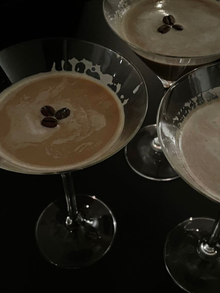 three martini glasses filled with liquid and topped with an almond on the rim, sitting next to each other