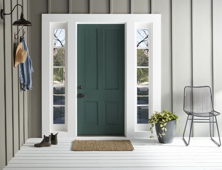 a blue front door with two chairs and a potted plant on the porch next to it