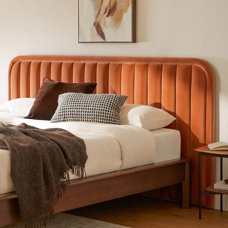 a bed with an orange headboard and two pillows on it, in a bedroom