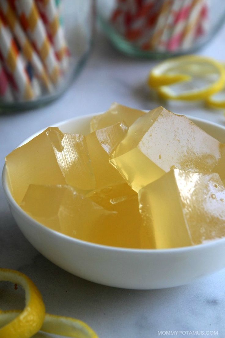 a white bowl filled with yellow liquid next to sliced lemons