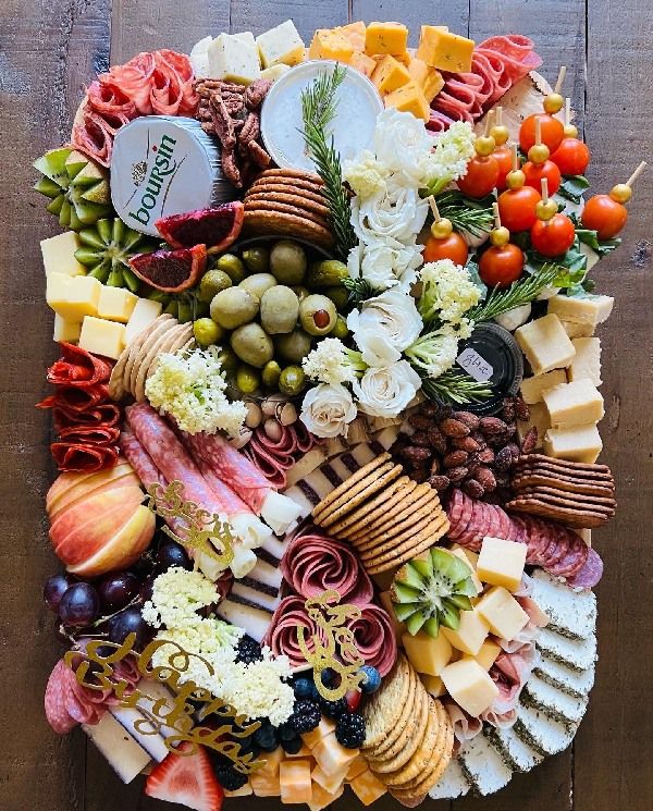 a platter filled with lots of different types of cheeses and crackers on top of a wooden table