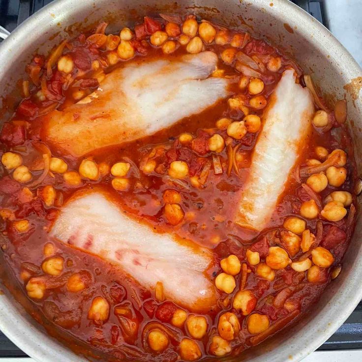 fish and chickpeas are cooking in a pot on the stove top, ready to be cooked