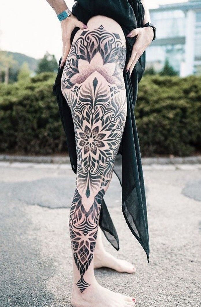 a woman with tattoos on her legs and leggings is standing in the street