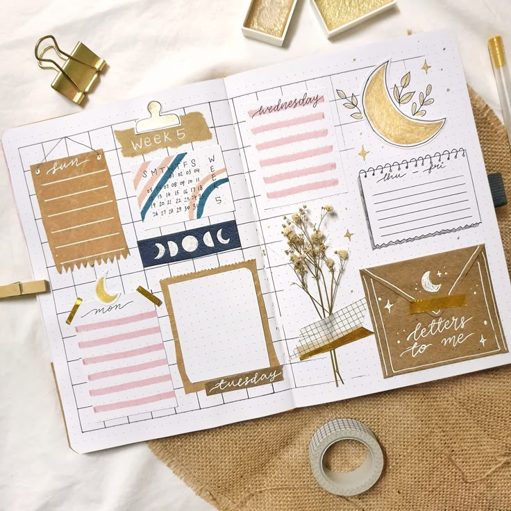 an open planner with gold foil and paper on it, next to some other items