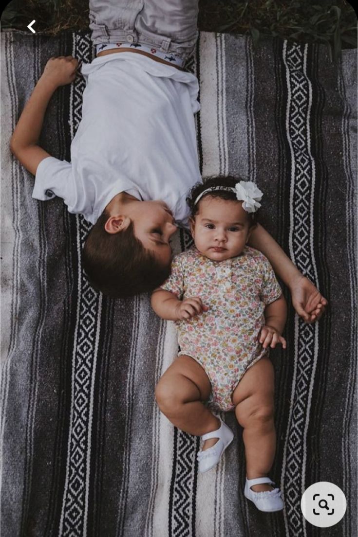 two babies laying on top of a blanket next to each other