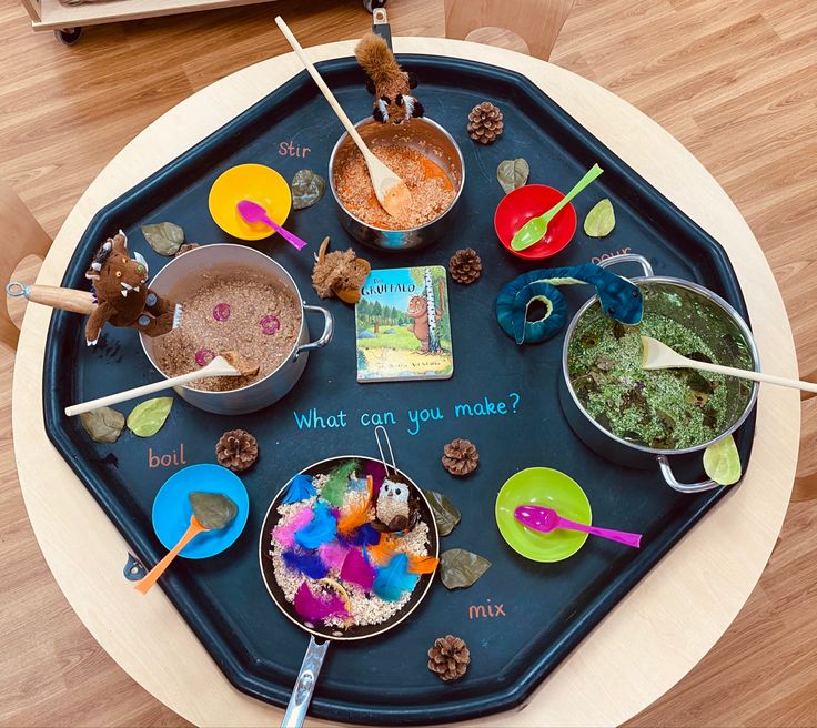 a child's play tray with spoons, bowls and food on it that says what can you make?