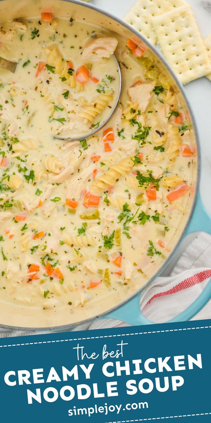 a pot filled with chicken noodle soup next to crackers and cheese on the side