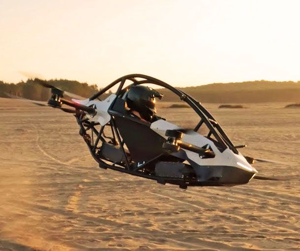 a person in a vehicle flying through the air on top of sand covered ground at sunset