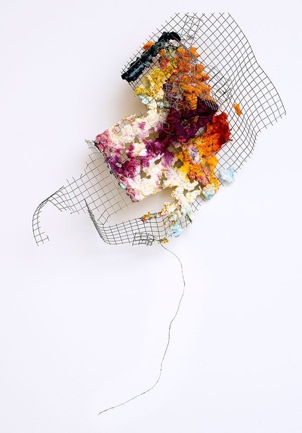 a piece of cake sitting on top of a mesh net covered tablecloth next to a white wall