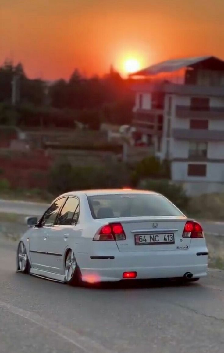 a white car driving down the road at sunset