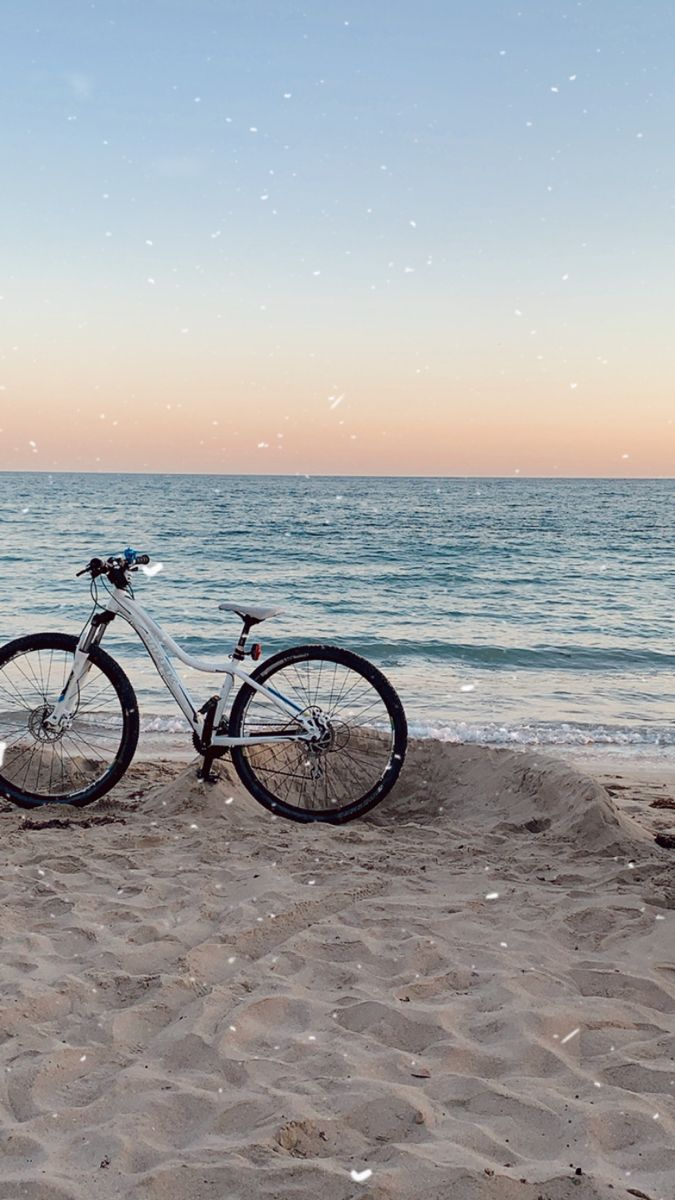 a bicycle parked on the beach next to the ocean