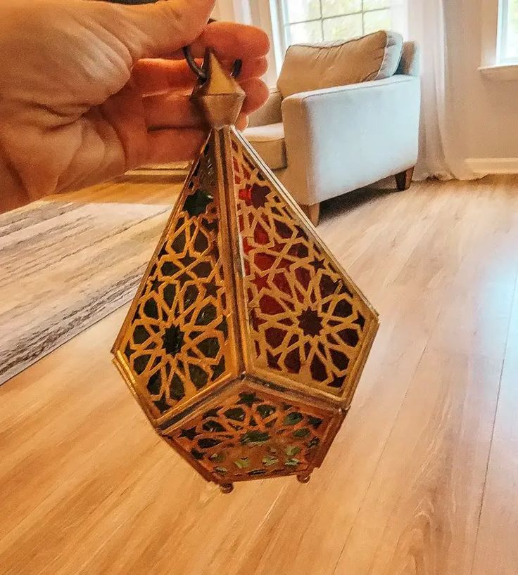 a hand holding a small decorative object in the middle of a living room with hardwood floors