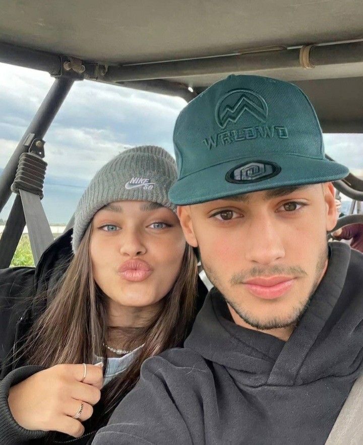 a man and woman in a golf cart posing for the camera with their hat on