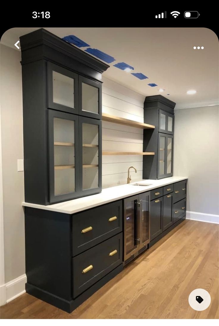 an empty kitchen with black cabinets and white counter tops on wooden flooring in front of a built - in oven