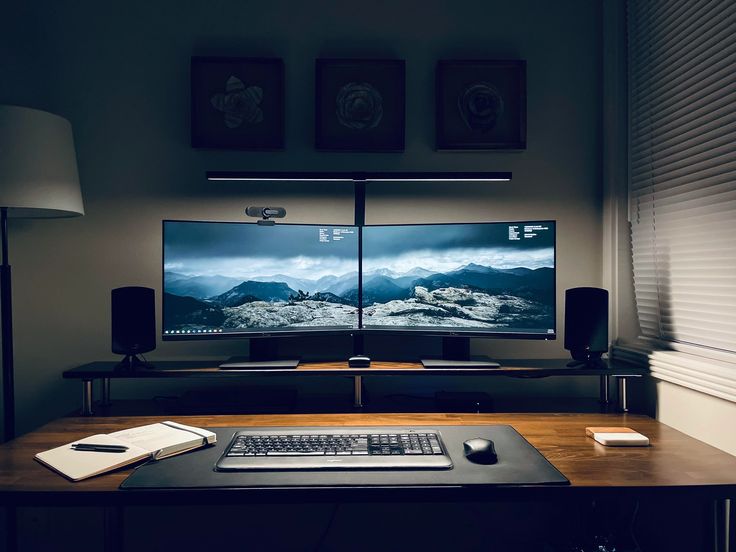 a computer desk with a monitor and keyboard on it in front of a wall mounted television