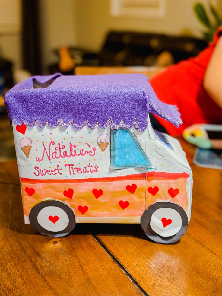 a paper model of a truck with hearts on the side sitting on a wooden table