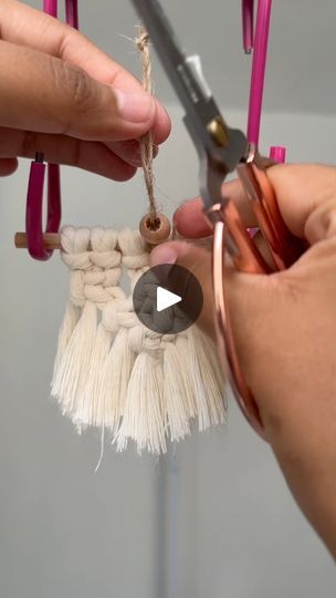 two hands are holding scissors and stringing the ends of a small piece of fabric