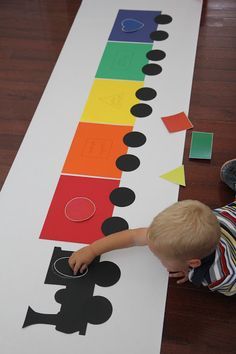 a little boy that is standing in front of a paper cut out with shapes on it