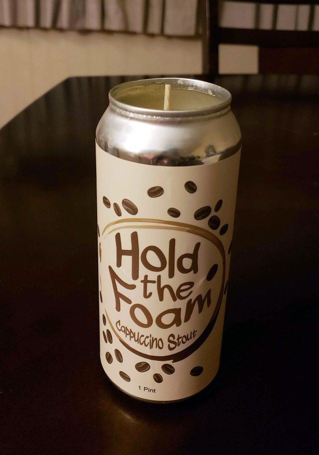 a close up of a can on a table with a candle in the middle and writing hold the foam