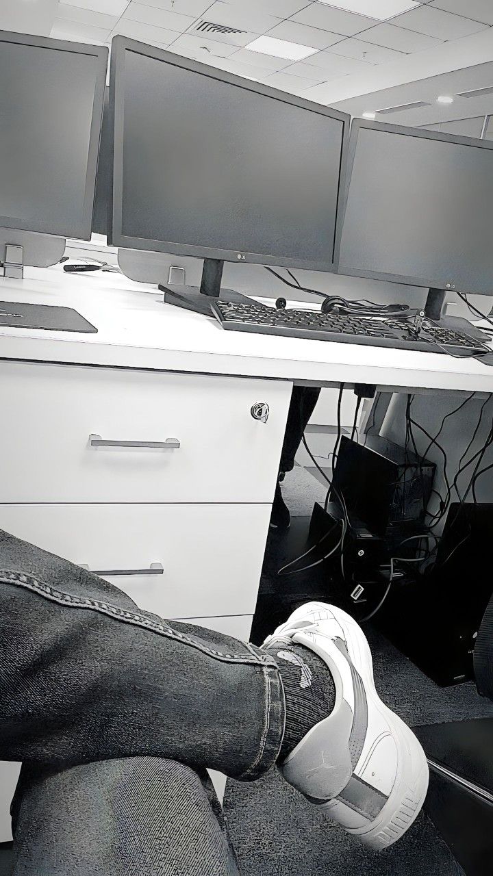 a person sitting at a desk with two computer monitors on it's sides and their feet propped up in front of them