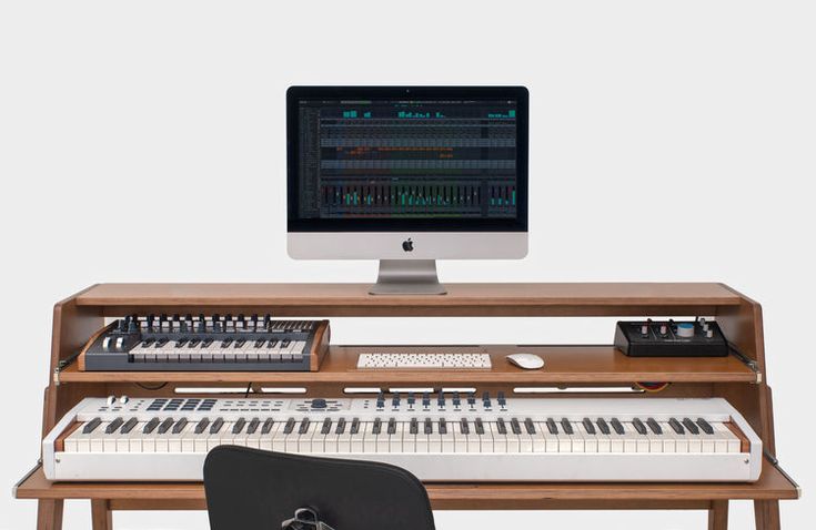 an electronic keyboard sitting on top of a wooden desk next to a monitor and keyboard