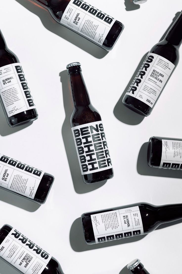 six bottles of beer sitting next to each other on a white surface with shadows from them