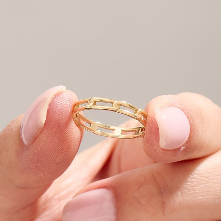 a woman's hand holding a gold ring