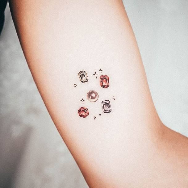 a woman's arm with four different colored jewels on the left side of her arm