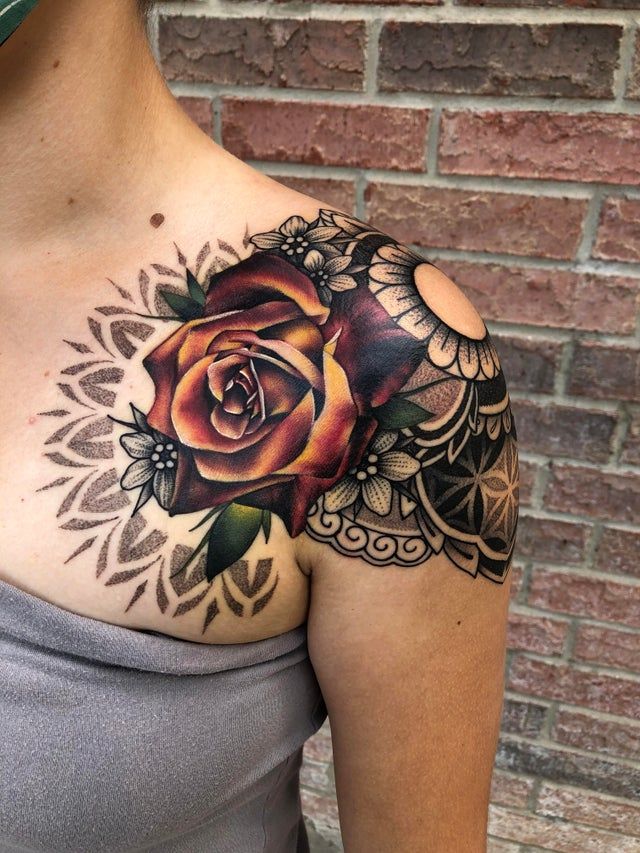 a woman's chest with a rose tattoo on her left shoulder and an intricate design