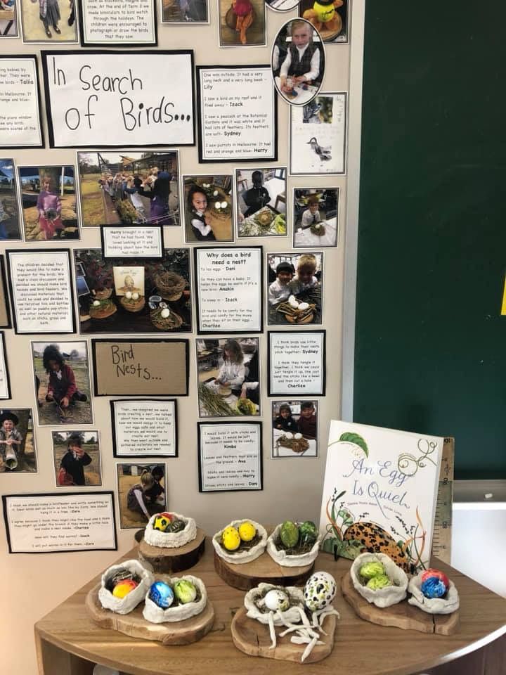 a table topped with bowls filled with food next to a green wall covered in pictures