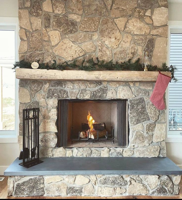 a stone fireplace with a lit candle and stockings hanging on it's mantel