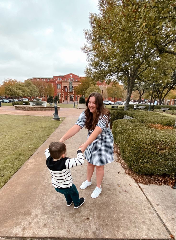 a woman holding the hand of a little boy