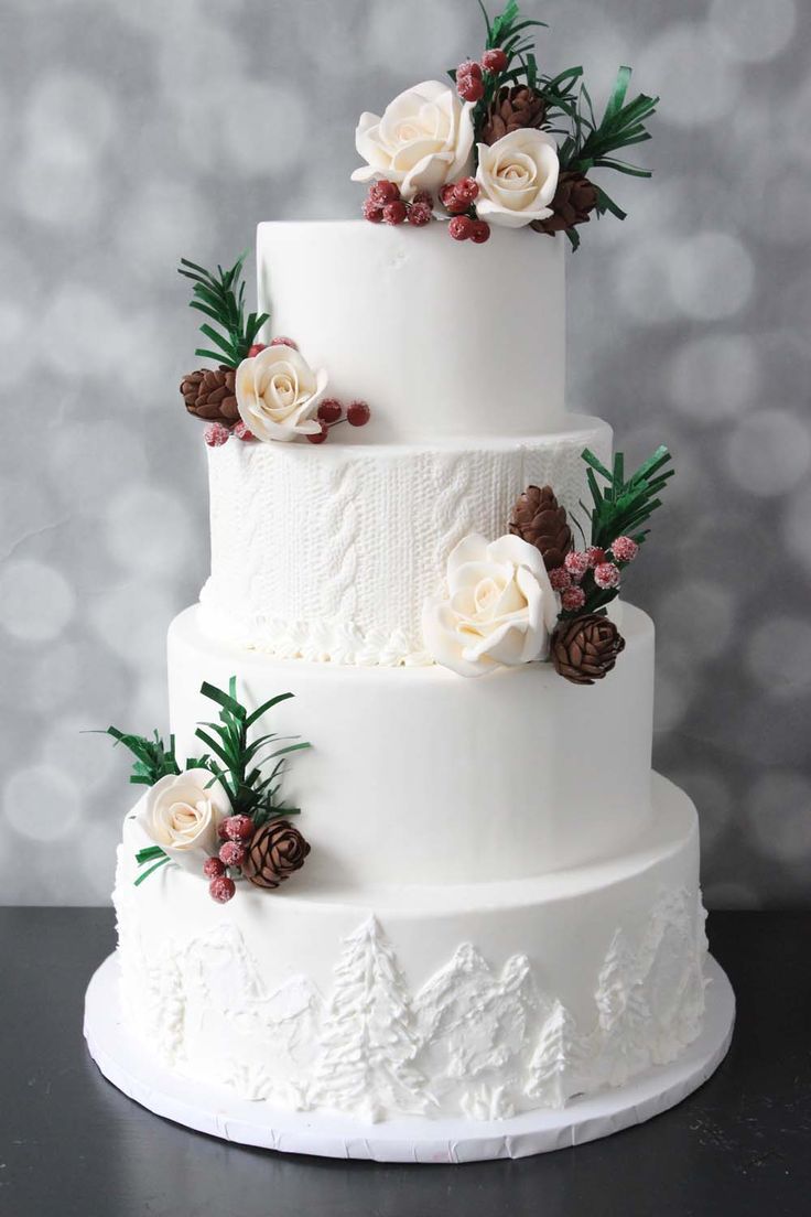 a white wedding cake with flowers and pine cones