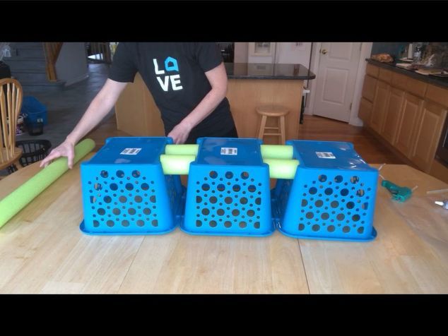 a person standing next to four blue crates on top of a wooden table in a kitchen