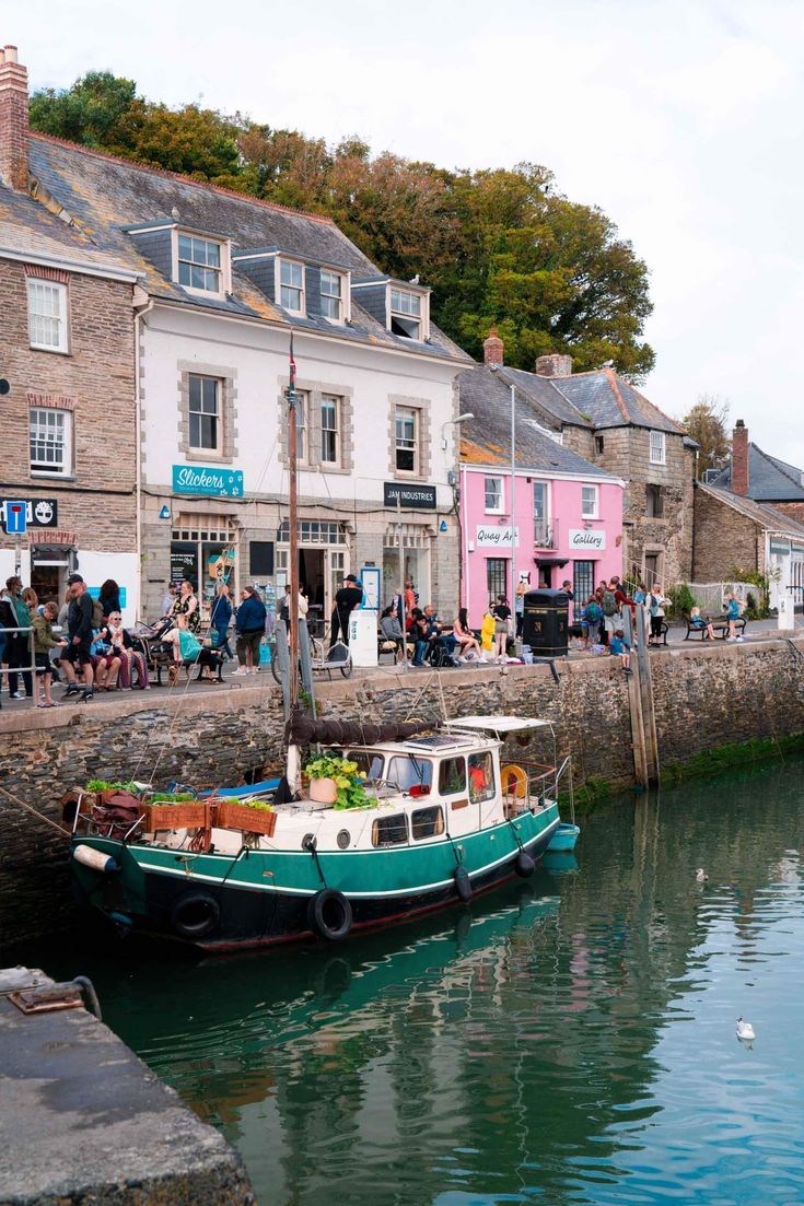 a boat is docked in the water next to some buildings and people are walking around