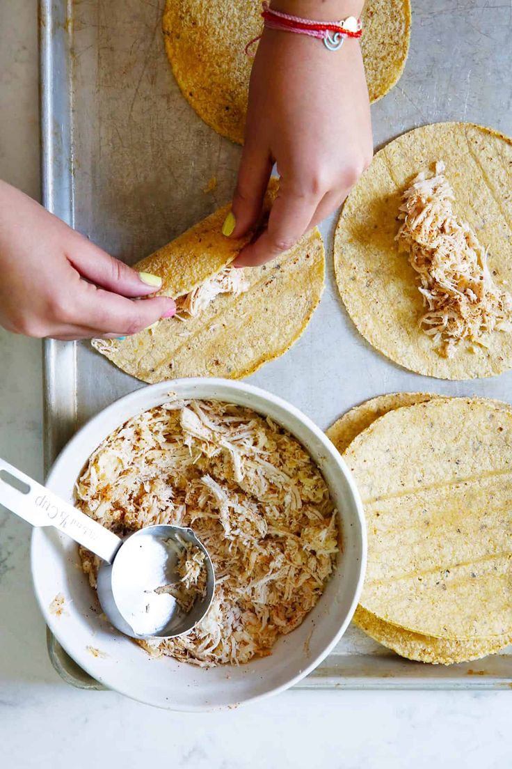 tortillas being made in a bowl with a spoon and two hands reaching for them